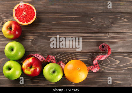 Obst und Maßband auf Holz- Hintergrund. Ernährung Lebensmittel Stockfoto