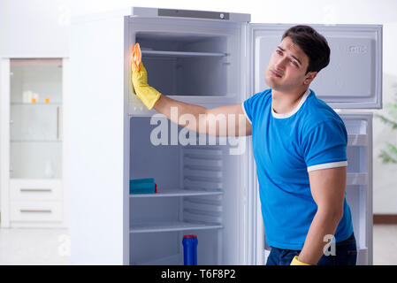 Mann Reinigung Kühlschrank im hygienekonzept Stockfoto