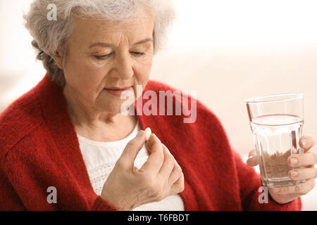 Ältere Frau die Pille auf hellen Hintergrund Stockfoto