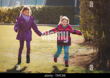 Zwei glückliche Mädchen/Geschwister laufen Hand in Hand Stockfoto