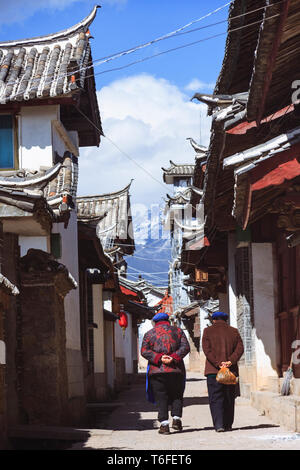 Lijiang, Yunnan, China: Zwei Frauen vorbei an traditionellen Naxi Architektur in der Altstadt von Lijiang, einem nationalen historischen und kulturellen Cit Stockfoto