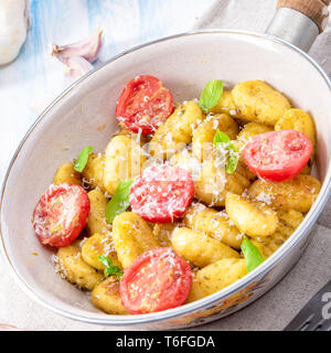 Gnocchi gebacken mit grünem Pesto, Kirschtomaten und Parmesan Stockfoto