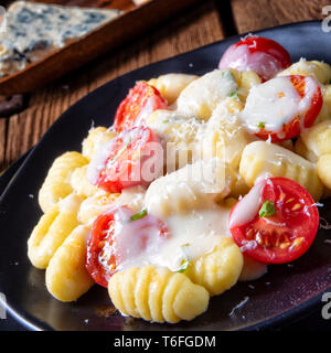 Gnocchi gebacken mit grünem Pesto, Kirschtomaten und Parmesan Stockfoto