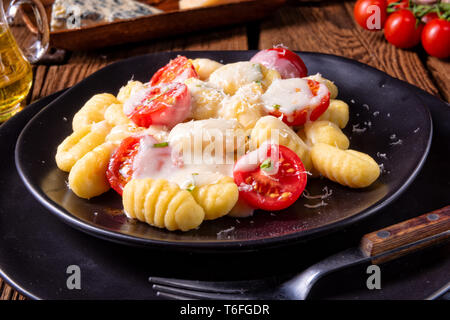 Gnocchi gebacken mit grünem Pesto, Kirschtomaten und Parmesan Stockfoto