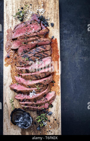 Traditionelle amerikanische Barbecue trockenen Jahren Flank Steak in Scheiben geschnitten als Close-up auf einem Holzbrett Stockfoto