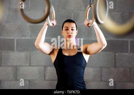 Junge weibliche Athleten konzentrieren, bevor Sie Arbeiten an den Ringen sich psyching Ihr Übungsprogramm im Inneren, eine Turnhalle zu beginnen. Stockfoto