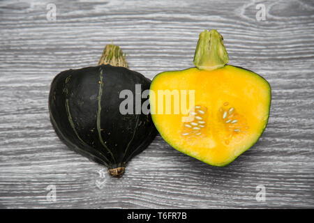 Homegrown organic Buttercup Squash schneiden Sie in der Hälfte Festlegung auf einem Holzbrett - dunkelgrün, hellgrün Schaft, goldgelb Fleisch und Samen. Stockfoto