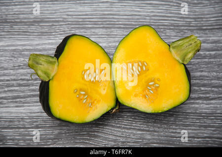 Homegrown organic Buttercup Squash schneiden Sie in der Hälfte Festlegung auf einem Holzbrett - dunkelgrün, hellgrün Schaft, goldgelb Fleisch und Samen. Stockfoto