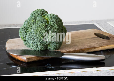 Brokkoli auf einem hölzernen Schneidebrett mit einem Edelstahl Messer bereit für das Abendessen zu geschnitten werden. Stockfoto