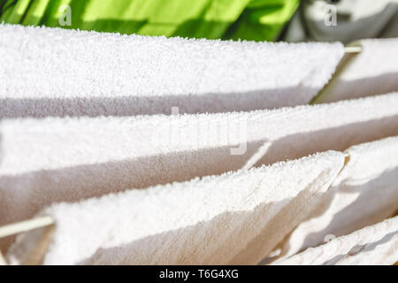 Weiße und farbige Bettwäsche und Handtücher auf der Wäscheleine getrocknet werden. Stockfoto