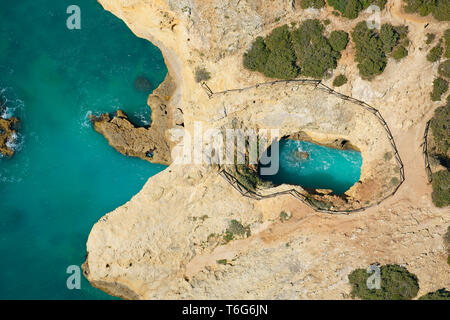 LUFTAUFNAHME. Meereshöhle / Sinkhole an der felsigen Küste in der Nähe des Strandes Cão Raivoso. Lagoa, Algarve, Portugal. Stockfoto