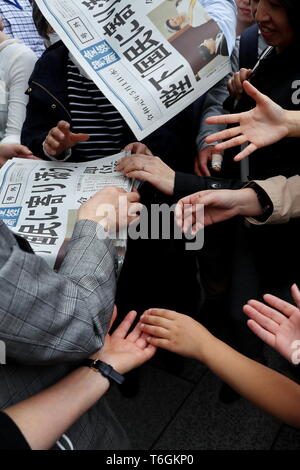 Die Leute versuchen eine Kopie von extra Ausgabe einer Zeitung, die über neue Kaiser Naruhito die Himmelfahrt auf der Vorderseite in Tokios Einkaufsviertel Ginza, Japan am 1. Mai 2019, dem ersten Tag der Reiwa Ära. Credit: Naoki Nishimura/LBA/Alamy leben Nachrichten Stockfoto