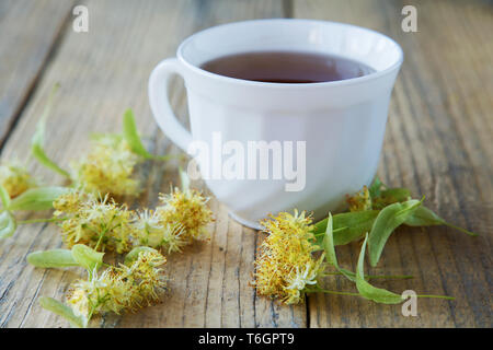 Tasse Tee mit Linden Blumen auf einem rustikalen Tisch Stockfoto