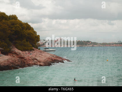 Die Sonnenstrahlen scheinen durch die Wolken über dem türkisfarbenen Meer am Strand von Palma de Mallorca, eine ruhige Szene mit einer Kopie des Raumes. Stockfoto