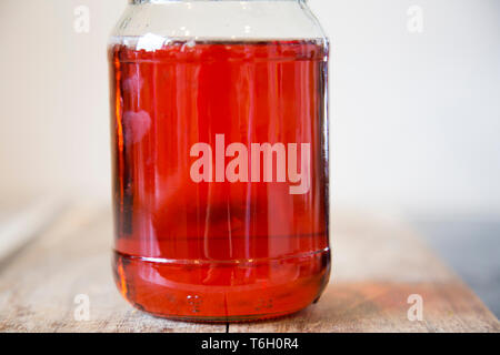 Hausgemachte Quittengelee in einem Glas mit einem schwarzen Deckel sitzen auf einem hölzernen Schneidebrett. Es ist mit unvollkommenen, organische homegrown Obst gemacht. Stockfoto