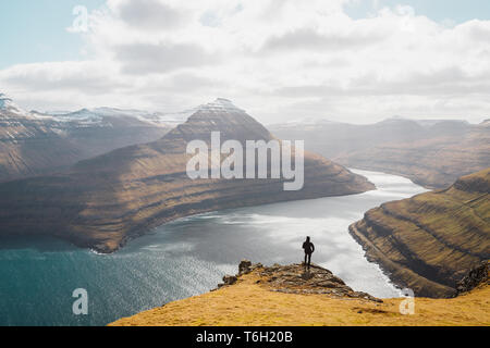 Einsamer Wanderer erfreuen sich an der Aussicht über spektakuläre Färöischen Fjord in der Nähe von Funningur an einem sonnigen Frühlingsmorgen (Färöer, Dänemark, Europa) Stockfoto