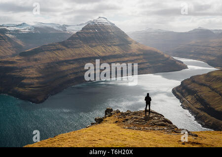 Einsamer Wanderer erfreuen sich an der Aussicht über spektakuläre Färöischen Fjord in der Nähe von Funningur an einem sonnigen Frühlingsmorgen (Färöer, Dänemark, Europa) Stockfoto