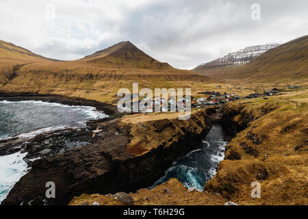 Panoramablick auf die Schlucht/natürlichen Hafen in Gjógv mit Wellen schlagen die Klippen und der Sonne im Hintergrund (Färöer, Dänemark, Europa) Stockfoto