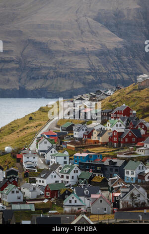 Blick auf das Dorf Eiði mit seinen bunten Häusern und der Kirche von eiði vor einer malerischen Gebirgskette (Färöer, Dänemark, Europa) Stockfoto