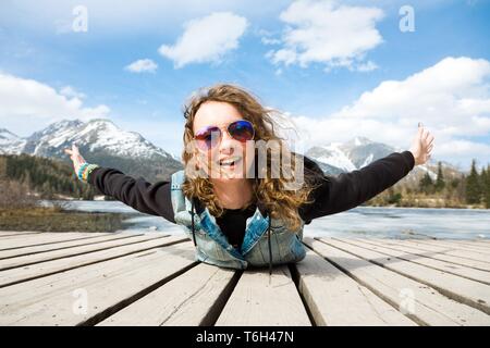 Junge Mädchen liegt auf Holzterrasse und Spaß haben - so fliegen wie ein Vogel - Willkommen Frühling Stockfoto