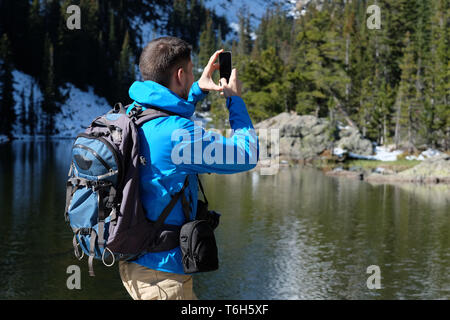 Backpacker unter Foto mit Smartphone Stockfoto