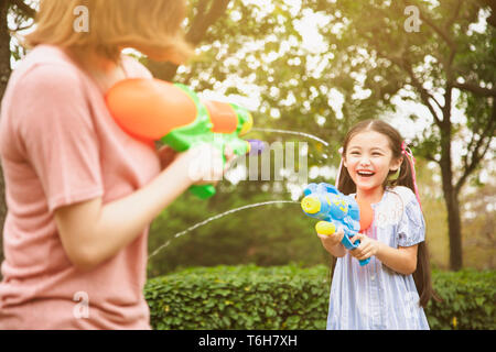 Mutter und kleinen Mädchen spielen Wasserkanonen im Park Stockfoto