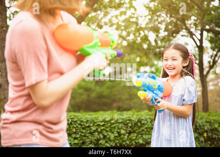 Mutter und kleinen Mädchen spielen Wasserkanonen im Park Stockfoto