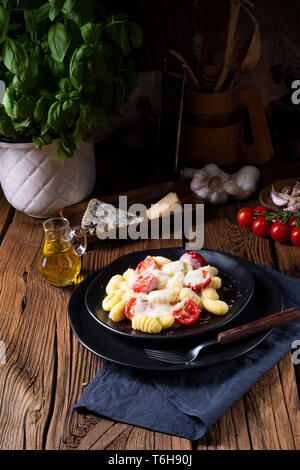 Gnocchi gebacken mit grünem Pesto, Kirschtomaten und Parmesan Stockfoto