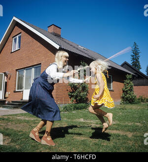 70er jahre lifestyle. Eine Mutter und ihre Tochter zusammen im Garten spielen. Sie sind Seilspringen zusammen und Lachen. Schweden der 70er Jahre. Sie ist Schauspielerin Margareta Sjödin. Stockfoto