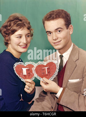 Paar von den 1950er Jahren. Eine junge Frau und Mann sind jeweils eine Holding in Herzform Papiere farbige in Rot mit Ornamenten um ihn herum. Eine Illustration für den Valentinstag. Schweden 1950. Stockfoto