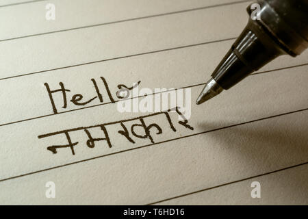 Anfänger Hindi Sprache Lernende schreiben Hallo Namaste Wort in der indischen Hindi Alphabet auf einem Notebook Nahaufnahme Stockfoto