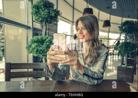 Schöne Frau unter selfie in einem Café. schöne Frau, ihr Telefon verwendet, wie ein Spiegel. Junge Mädchen an Restaurant, self portrait Stockfoto