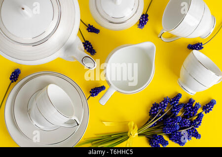 Weißes Porzellan Kaffee oder Tee mit muscari Blumen auf gelb hinterlegt. Ansicht von oben. Flach. Stockfoto