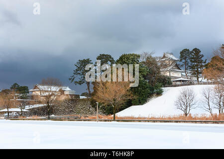 Fernsicht auf das Kahokumon Tor und der 'Hishi' Yagura, Revolver, von Kanazawa Castle. Stürmischen dunklen grauen Himmel Overhead, Schnee, der Boden. Stockfoto