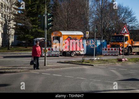 Eine ältere Frau wartet eine vielbefahrene Straße in Berlin, Deutschland. Stockfoto