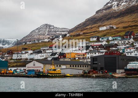 Malerischen bunten Häuser in der kleinen Stadt Klaksvík vor schneebedeckten Bergen wie von einer Fähre zur Insel Kalsoy gesehen (Färöer Inseln) Stockfoto