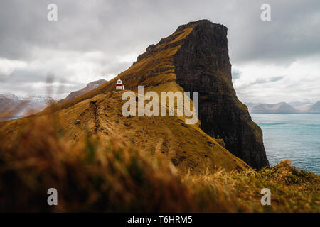 Blick auf malerische Kallur Leuchtturm auf Kalsoy Insel mit einsamen Wanderer auf einer Klippe mit Blick auf türkisblaue Atlantik (Färöer, Dänemark, Europa) Stockfoto