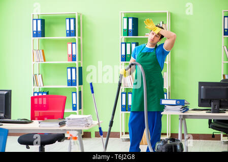 Schöner mann Büro mit Staubsauger reinigen Stockfoto