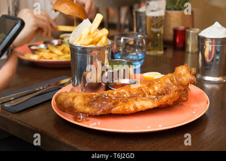 Britische traditionelle Fisch und Chips mit Kartoffelpüree Erbsen auf dem Tisch. Stockfoto