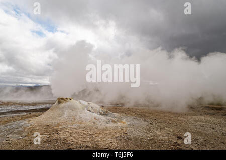 Vulkanische Landschaft mit einer großen Fumarole, die eine Menge Dampf löst, im Hintergrund weiter Dampf, Wind lässt den Dampf in der Horizontalen Stockfoto