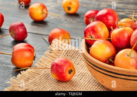 Paradies Äpfel in eine Schüssel geben und auf einen dunklen Tisch verstreut Stockfoto