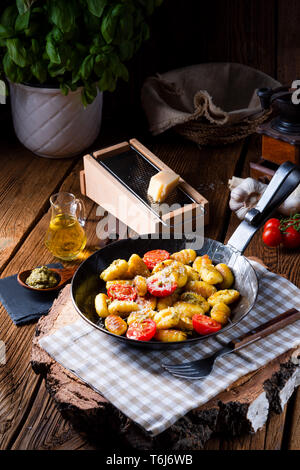 Gnocchi gebacken mit grünem Pesto, Kirschtomaten und Parmesan Stockfoto