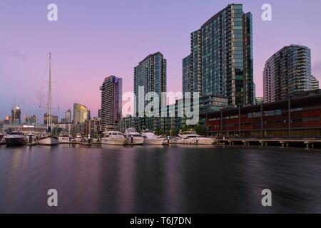 Victoria Harbour Promenade Melbourne Docklands Marina und hohen Apartment Gebäude in rosa und lila Farbtönen von Sunset Stockfoto