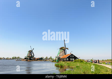 Zaanse Schans, Niederlande - 22 April 2019: Touristen sightseeng berühmte traditionelle holländische Windmühlen in der "Zaanse Schans", ist eine typische kleine Dorf innerhalb Stockfoto