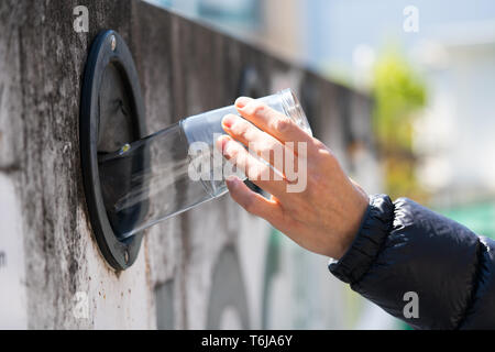 Detailansicht einer weiblichen Hand recycling Glas der Umwelt an Ihrem lokalen Recyclinganlagen zu speichern. Stockfoto