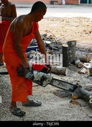 Ein buddhistischer Mönch tragen Safranroben schneiden ein Protokoll mit einer Kettensäge. Kampong Thom, Kambodscha, 20-12-2018 Stockfoto