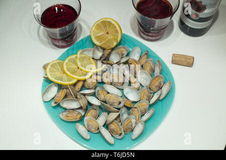 Lecker clam Spisula-muschel-auf Folie Kochen im Ofen gegrillte Neben Gläsern und einer Flasche roten Granatapfel Wein Stockfoto