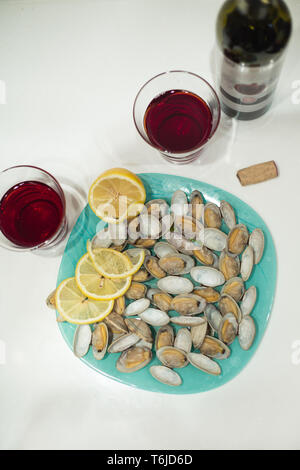 Lecker clam Spisula-muschel-auf Folie Kochen im Ofen gegrillte Neben Gläsern und einer Flasche roten Granatapfel Wein Stockfoto