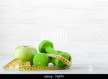 Fitness und gesunde Ernährung Konzept. Hanteln und Apple auf hölzernen Tisch. Mit Platz für Ihren Text kopieren Stockfoto
