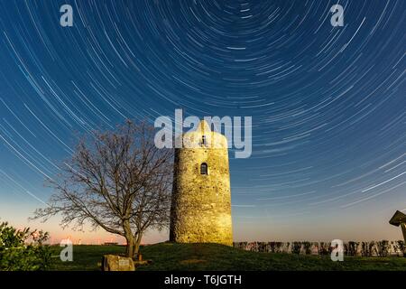 Alten Wachturm in der Nacht vom Vollmond beleuchtet, mit rotierenden Sky (Star Wanderwege) Stockfoto